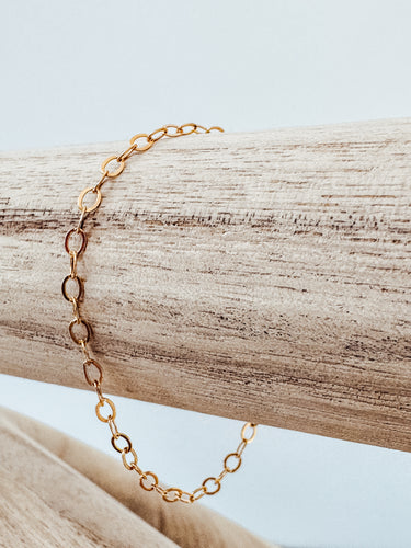 Levvet gold-plated chain bracelet laid out on a wooden surface by Matte Jewelry