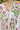 Woman wearing Lissandra Maxi Dress with pink and green floral print walking outdoors in garden setting close up