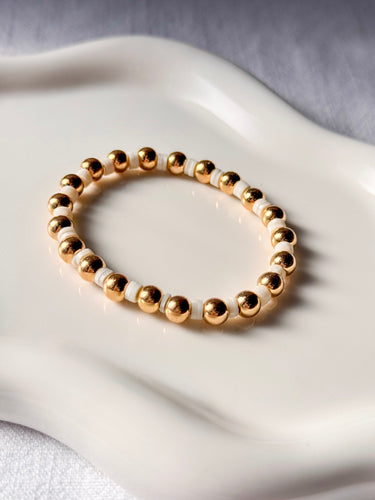 Lunaire gold stretch bracelet with white beads by MatteGold on a white surface