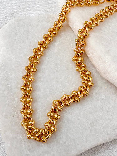 Gold chain anklet on a marble surface
