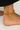Gold anklet on a foot against a neutral background