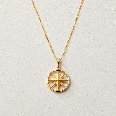 Marin Necklace by Matte featuring a delicate gold-tone chain with a polished round compass star pendant displayed on a soft textured white background.