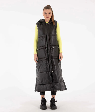 Front view of woman wearing long black hooded puffer vest with quilted design.