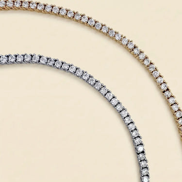 Mika Necklace luxury tennis necklace with brilliant simulated diamonds in gold and silver finishes on neutral background.