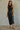 Woman wearing the Montauk Top in black, featuring a sleeveless ribbed knit design, fitted cropped silhouette, soft stretch fabric, and a flattering high neckline styled with a satin midi skirt.