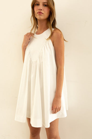 Model wearing Nara Mini Dress in white with halter neckline and relaxed fit.