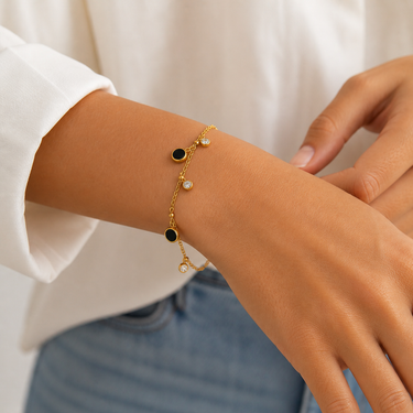 Model wearing the Nau Bracelet featuring a delicate gold chain with black enamel charms and crystal accents.