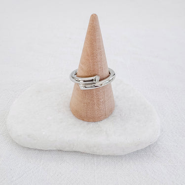 A gold-plated ring displayed on a white ring stand with a textured background.