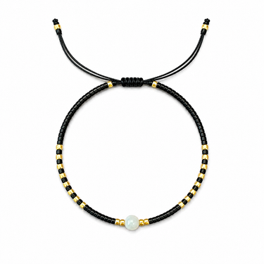 Nodath Bracelet black adjustable beaded bracelet with gold accents and ivory stone centerpiece on white background.