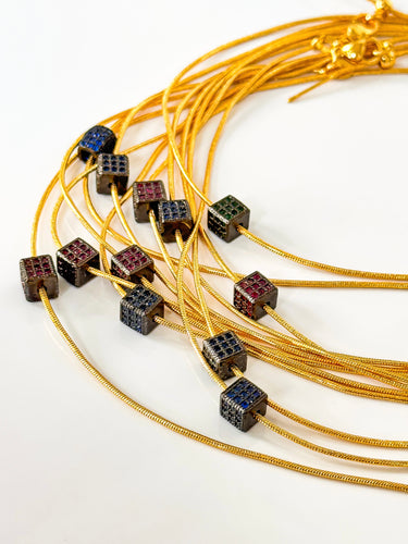 Noir & Gold Pavé Necklace by Matte, gold chain with cube pavé gemstones in purple, green, and blue on white background