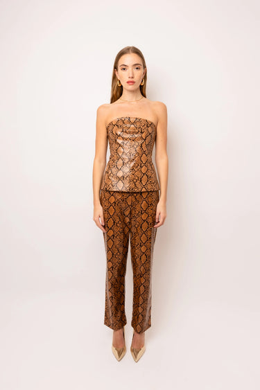 Editorial shot of the Nomi Bandeau Top in metallic bronze snake print, styled with gold jewelry and matching pants, Matte fashion.