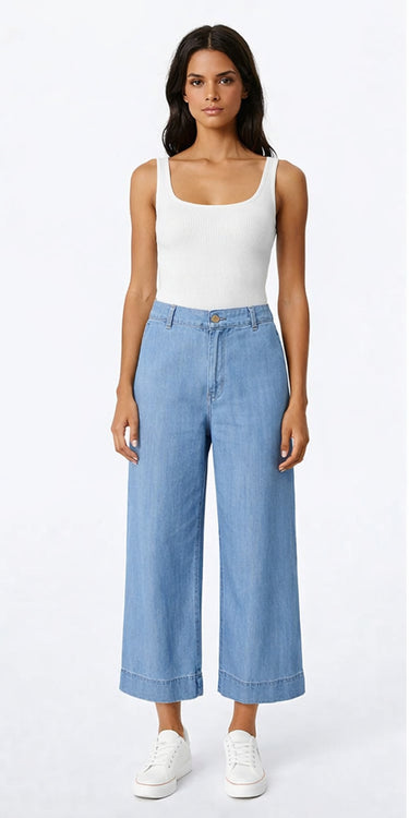 Wide-leg Tencel pants in light blue with relaxed drape and high-rise fit, photographed on a model wearing a white top in a bright neutral studio.