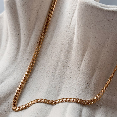 Palmeira gold plated chain necklace by Matte, classic flat chain displayed on neutral fabric
