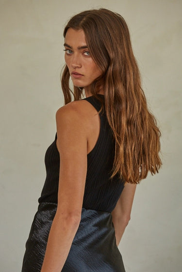 Regi Top side view of black sleeveless ribbed tank top with close fit silhouette.