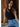 Woman wearing the Romett Top in black, featuring a ribbed knit fabric, sleeveless design, high neckline, fitted silhouette, cropped length, and soft stretch material styled with light-wash high-rise jeans.