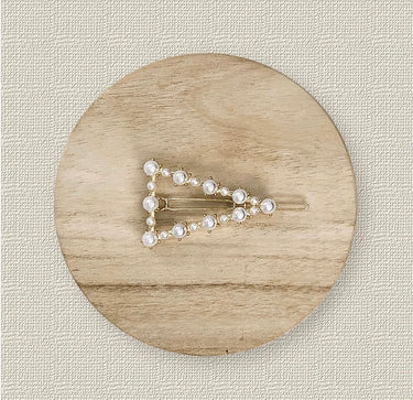 Sabo Hair Clip with gold triangle shape and pearl accents on wood background, elegant accessory photo for Matte.