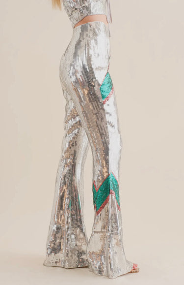 Silver sequin pants with bold green and red lightning bolt detail, high-waisted flared fit, side view.