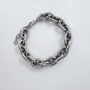 Silver chunky chain bracelet with polished oval links and small heart charm on clasp, displayed on white background