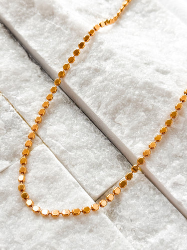 Stage Necklace by Matte, gold plated coin chain on textured white surface