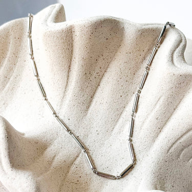 Teresina Necklace by Matte, silver tube chain on cream textured surface