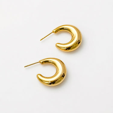 Turnhout Hoop Earrings featuring polished gold-plated sculptural hoop earrings with a twisted C-shaped silhouette, smooth mirror finish, lightweight hollow design, secure post-back closure, and modern statement style.