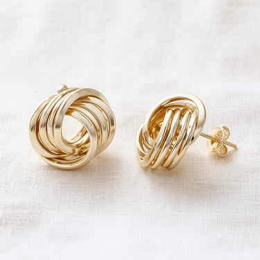 Gold twisted knot stud earrings on white linen backdrop, Vail Stud Earrings.
