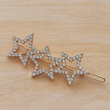 Gold triple star hair clip with crystal accents on wood background – Ventura Hair Clip by Matte.