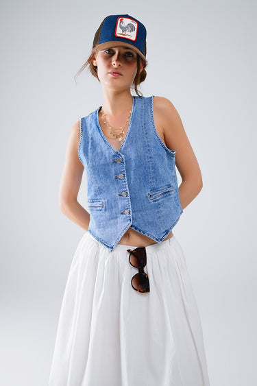 Woman wearing a denim vest and white pants with a plain background