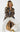 Woman wearing brown Wave Cardigan with abstract knit design, styled with beige pants and gold accessories.