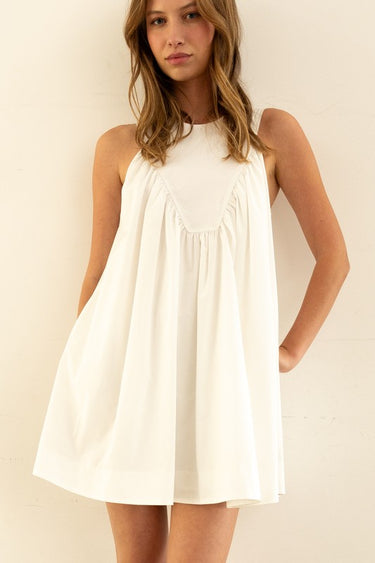 Model wearing Nara Mini Dress in white with halter neckline and relaxed fit.