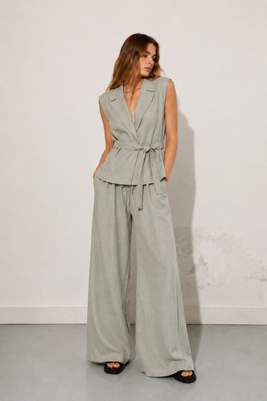 Woman wearing the Wilkin Set in a soft sage linen-blend fabric, featuring a tailored sleeveless vest, high-waisted wide-leg pants, relaxed fit, breathable woven texture, and an effortlessly elegant silhouette.