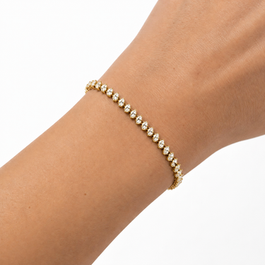 Zarik Bracelet gold tennis bracelet worn on wrist featuring sparkling cubic zirconia accents.