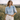 Matte All Tops collection image – model wearing a light blue denim puff-sleeve blouse with cream shorts in a sunlit countryside field