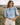 Matte All Tops collection image – model wearing a light blue denim puff-sleeve blouse with cream shorts in a sunlit countryside field