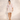 Matte Mini Dresses collection image – model wearing a pastel floral mini dress with lace trim and puff sleeves against a warm off-white stucco wall in natural sunlight