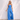Matte Jumpsuits collection image – model wearing a bright blue strapless wide-leg jumpsuit against a textured white wall in soft natural sunlight