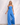 Matte Jumpsuits collection image – model wearing a bright blue strapless wide-leg jumpsuit against a textured white wall in soft natural sunlight