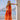 Woman wearing an orange tie-dye maxi dress styled on a Mediterranean terrace with ocean view