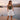 Matte Shorts collection image – model wearing white broderie lace shorts with an olive tank top on a wooden dock by a Patagonian lake with mountains in the background