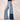 Matte All Jeans collection image – model wearing two-tone patchwork wide-leg denim jeans with a black top against a textured white wall in warm natural sunlight