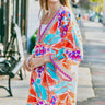 Model wearing Addison Dress with bright tropical print and kimono sleeves.