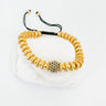 A gold-colored adjustable bracelet with a mix of round and link chains, featuring a spherical charm with a black and white pattern.