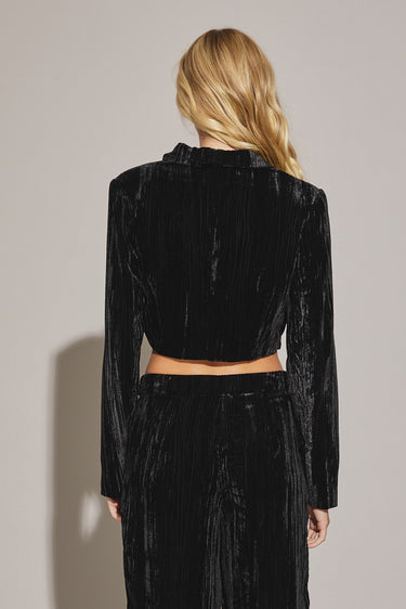 Woman wearing black Akima cropped velvet jacket with matching pants, full look back view.
