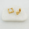 A pair of Alejandrina gold-plated huggie earrings on a white surface, displaying their square shape and closed loop design.