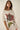Alina Tee oversized cream graphic t-shirt with vintage-inspired red floral bloom and green leaves print, relaxed fit short sleeves, styled casually on model against neutral studio background.