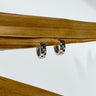 A pair of Anais gold-plated huggie earrings displayed on a wooden surface.