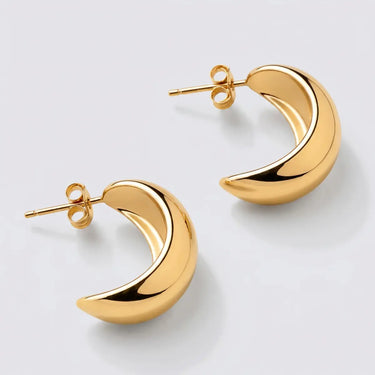 Gold crescent hoop earrings with a polished chunky silhouette and rounded open design on a light gray background.