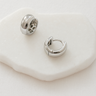Arden Huggie Earrings — silver mirror-plated rounded huggies on white stone background, sleek and minimalist jewelry by Matte.