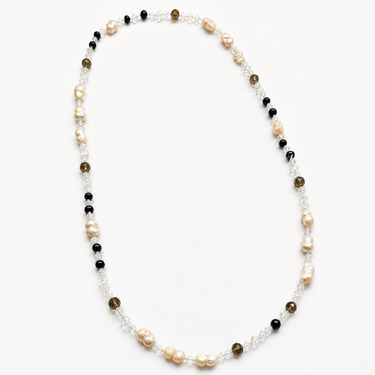Aureat Necklace flat lay showing mixed pearl, crystal, and dark bead design with long silhouette detail.