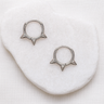 Auri Huggie Earrings — silver spike-detail huggies on white stone background, bold, polished, and lightweight jewelry by Matte.